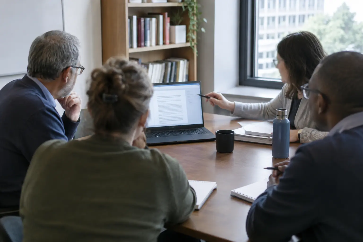 A faculty committee reviewing a shared document together at a table